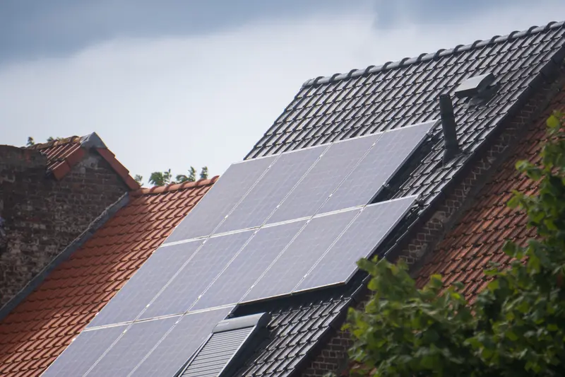 Panneaux solaires noirs posés au ras d'une toiture ancienne en tuiles